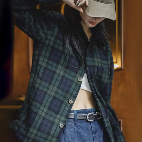 Person wearing a green plaid shirt and blue jeans with a blurred background